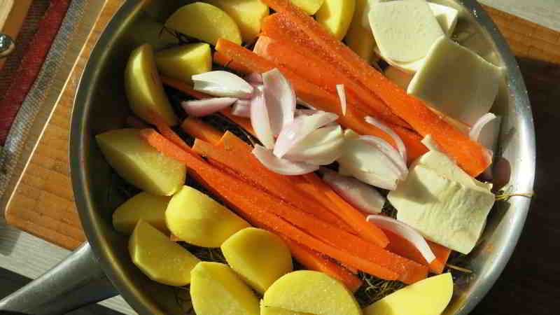 Kartoffel, Möre, Knoblauch, Pastinake, Schalotte und rote Zwiebel in einem Heubett gegart
